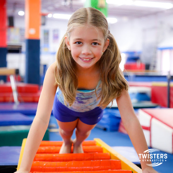 Smiling gymnast girl in pigtails on ladder at Twister Gymnastics of Boca Raton